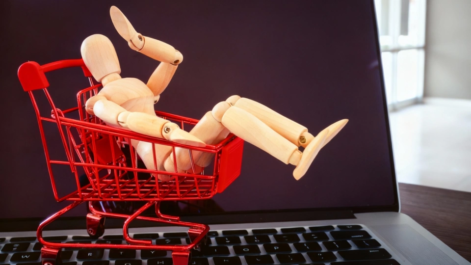 Koláž figuríny v nákupním košíku na klávesnici notebooku