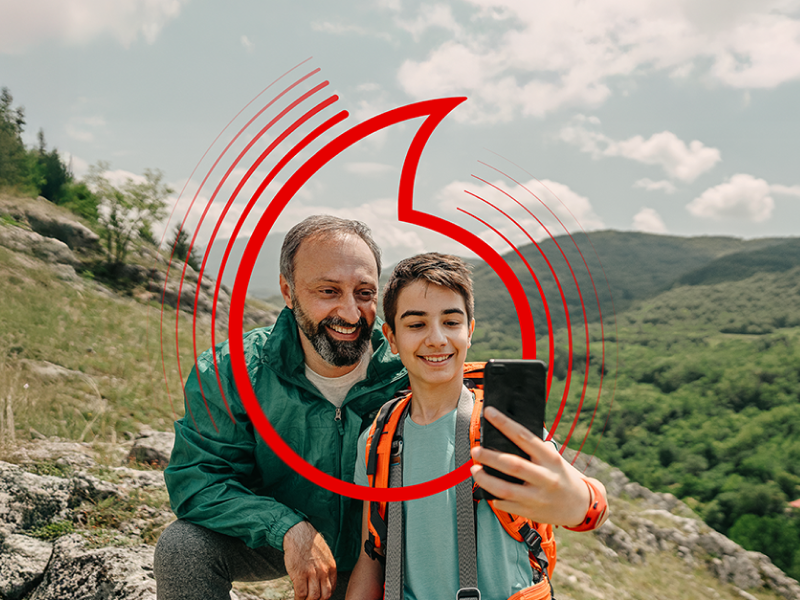 Matka a dcera společně sledují obrazovku mobilního telefonu v kuchyni